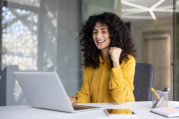 istock Successful businesswoman at workplace inside office at work, celebrating victory and triumphant achievement results. Company employee holding hand up, celebrating 2229195529