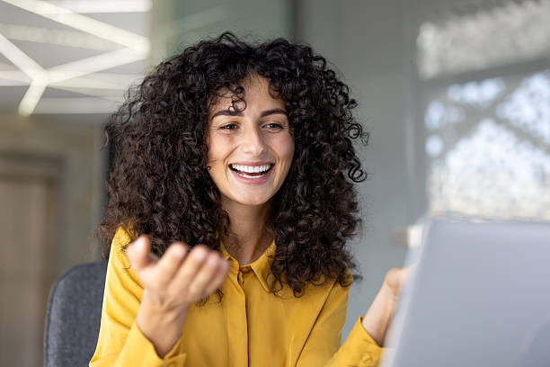 istock An attractive woman with curly hair laughs while interacting on a video conference call with colleagues. 2229195540