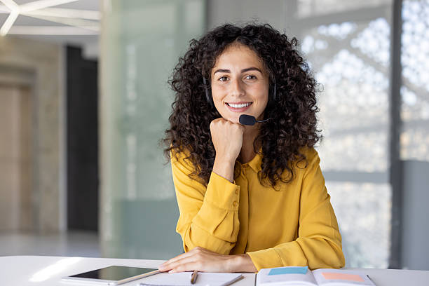 istock Attractive woman wearing a headset smiles while offering customer service from an office. 2229195566