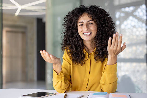 istock A smiling woman with curly hair gestures as if explaining or presenting. 2229195573