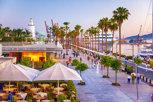 Seaside promenade at Malaga port, featuring modern walkways, vibrant shops, cafes, and stunning views of the Mediterranean Sea and docked yachts