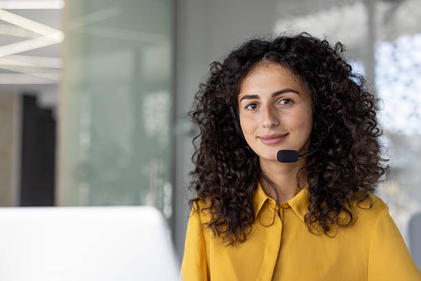 istock Smiling customer service representative with curly hair wearing a headset, ready to assist. 2229198736