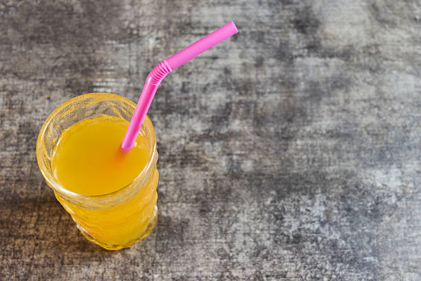 Refreshing orange drink served with a pink straw on a textured surface. High quality photo