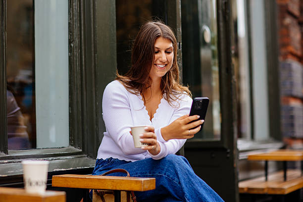 istock Happy young woman using mobile phone and enjoying coffee at cafe 2229200039