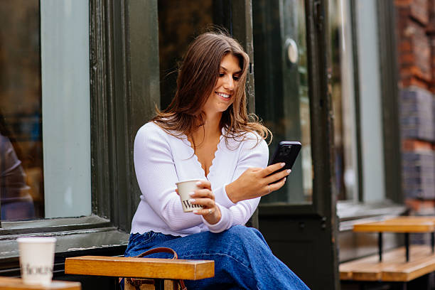 istock Happy young woman using mobile phone and enjoying coffee at cafe 2229200074
