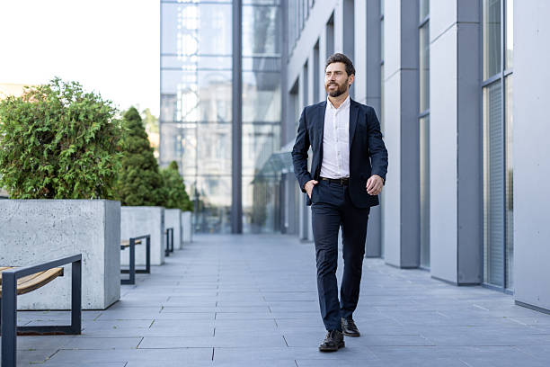 istock A stylish, professional man strides purposefully through a modern urban setting, looking ahead. 2229206592