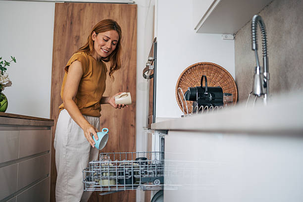 Woman emptying dishwasher in modern kitchen