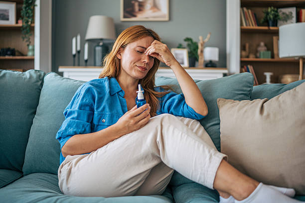 istock Sick woman using nasal spray at home on sofa 2229207682