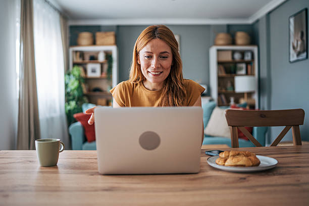 istock Smiling woman working from home using laptop at the table 2229207983
