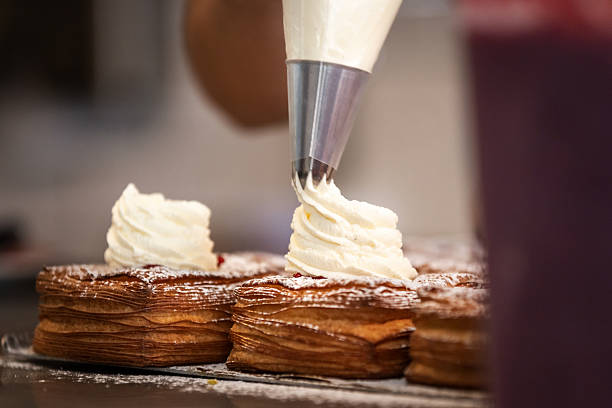 Unrecognizable woman is preparing pastry with fresh cream.