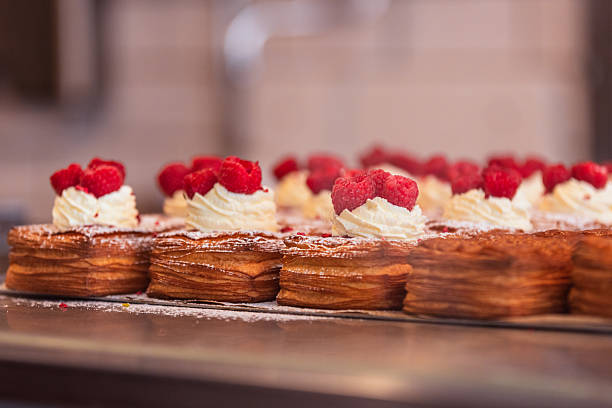 Baked pastry with cream and raspberry stands on bakery stall.
