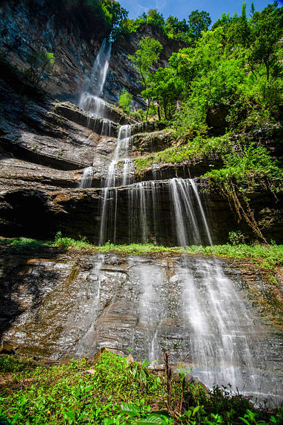 istock A stunning multi-tiered waterfall cascading down rocky cliffs surrounded by lush greenery. 2229217888