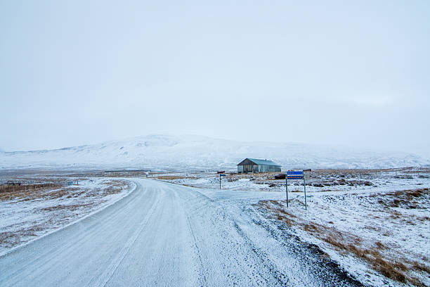Snow-covered road stretching into the distance through the Icelandic highlands. The minimal, remote winter landscape creates a sense of isolation and vastness.