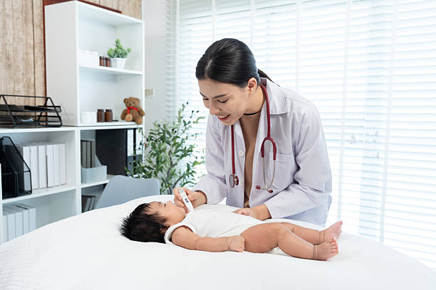 istock Smiling pediatrician checking newborn's temperature with a digital thermometer, creating a warm, reassuring, and child-friendly healthcare environment in a modern clinic. 2229229411