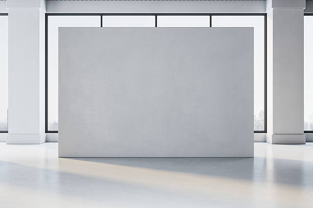 istock Empty grey exhibition wall in modern gallery room with large windows and city view in background, perfect for artwork or poster mockup display. 3D Rendering 2229232819