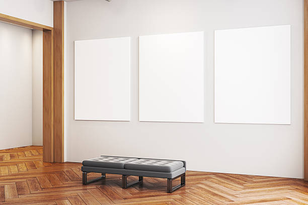 istock Contemporary gallery interior with three blank vertical posters on wall and bench on wooden floor under spotlight in exhibition room template. 3D Rendering 2229232884