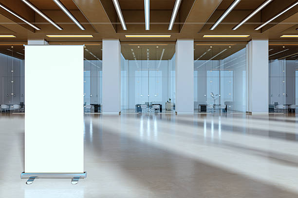 istock Blank roll-up banner stand mockup in modern spacious corporate office lobby interior with glass walls and lights on ceiling. 3D Rendering 2229233010