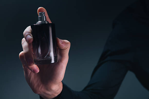 istock female hand with bottle of perfume on dark background 2229235404
