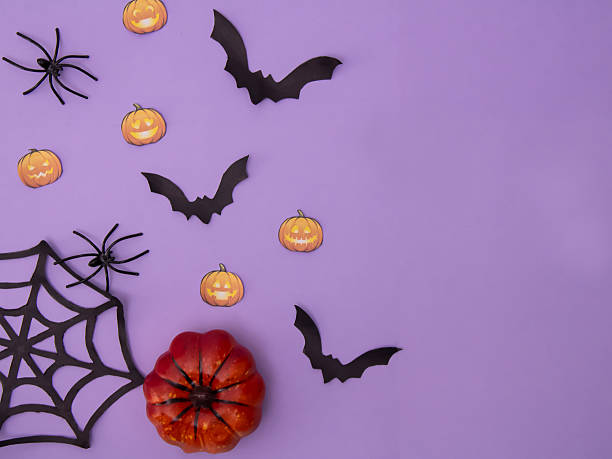 A flat composition with pumpkins, a spider web and a bat on a purple background, a place for text.