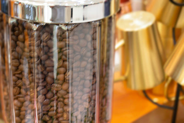 Large glass jars filled with roasted coffee beans and round waffle cookies displayed on a shelf.