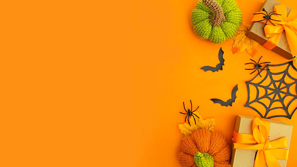 istock Knitted orange pumpkins and black bats on an orange background, autumn composition, front view.Happy Halloween holiday concept. 2229241595