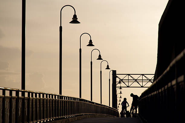 Silhouetted Father waits for child to catch up on a hill