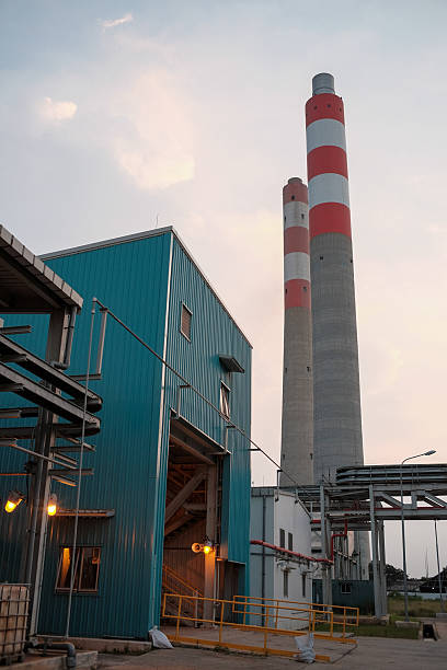 istock Industrial Complex with Striped Smokestacks Under a Light Sky, Showing Blue Building Facade and Supporting Steel Structures, Symbolizing Power Generation and Infrastructure Resilience 2229249209