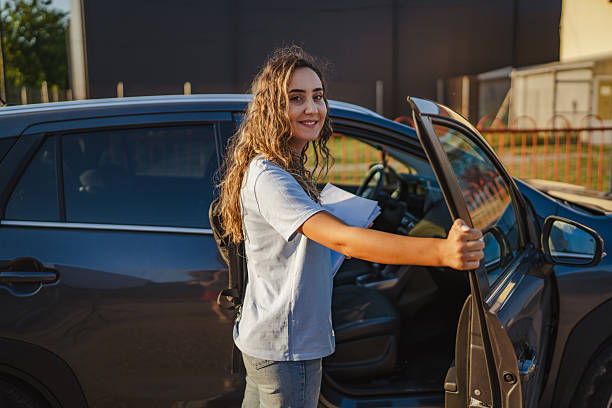 istock Smiling student getting out of car holding documents 2229252286