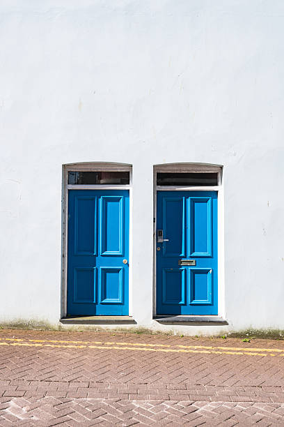 Two bright blue doors add a pop of color to a simple white wall in caernarfon, wales, creating a charming and welcoming scene