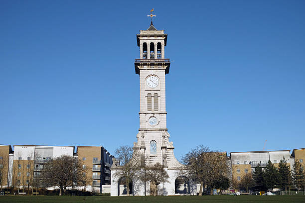 A clear daytime view of Chester's iconic clock tower, featuring its ornate ironwork and prominent clock face. The tower stands tall against a bright sky, surrounded by historic buildings and bustling streets. The well-preserved architecture highlights the timeless charm and rich heritage of the area.