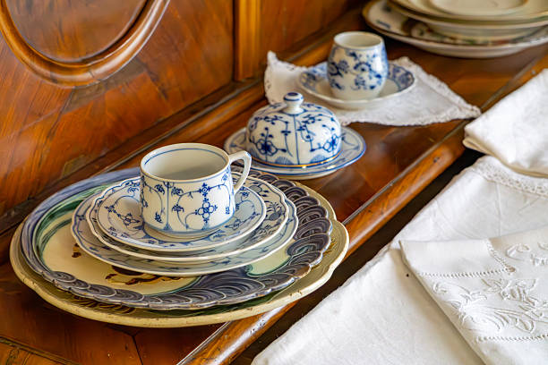 Antique porcelain cup and plate set with a blue pattern, arranged on a wooden sideboard with a lace doily.