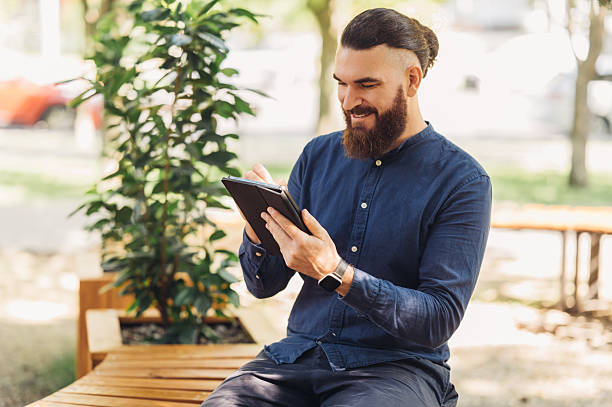 istock A man is enjoying using his tablet in an outdoor park setting surrounded by nature and greenery 2229274087