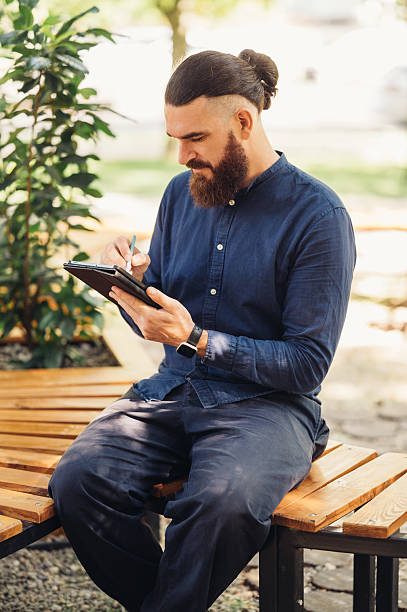 istock A man writes thoughtfully in a notebook outdoors, seeking creative inspiration in nature 2229276399