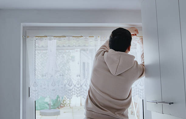istock A young man hangs a tulle curtain on the window. 2229279854