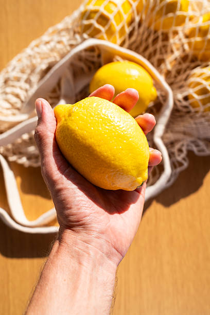 istock Hand holding a fresh ripe lemon in summer sunlight 2229280375