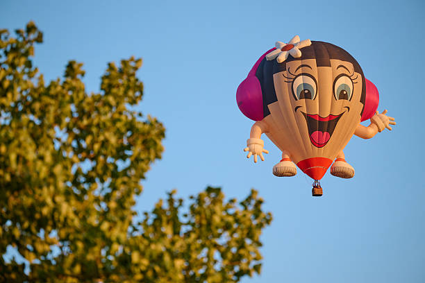 Grave , the Netherlands , international balloon festival. more than 35 hot air ballloons going in the air, funny balloon with hands and feet and a headphone and a flower in her hair
