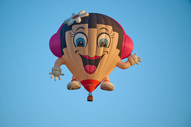 Grave , the Netherlands , international balloon festival. more than 35 hot air ballloons going in the air, funny balloon with hands and feet and a headphone and a flower in her hair