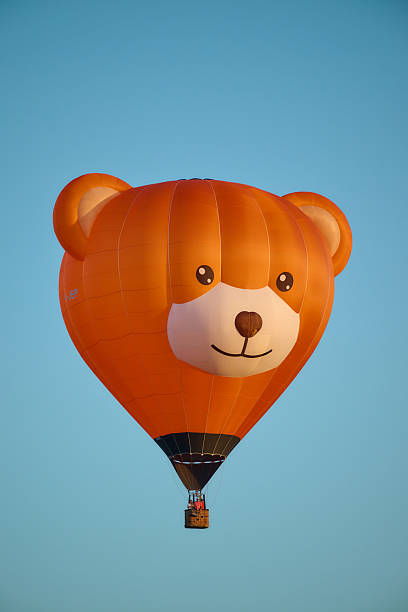Grave , the Netherlands , international balloon festival. more than 35 hot air ballloons going in the air, orange bear balloon frontal view