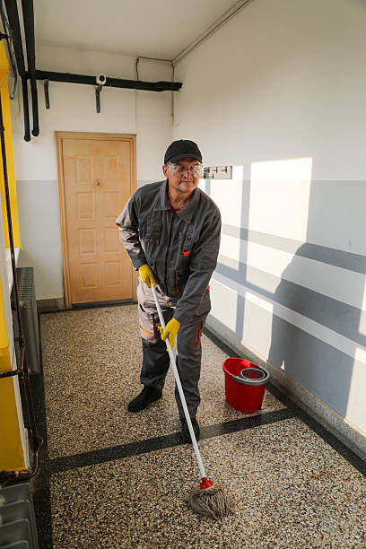 istock Older Worker in Cap and Overalls, Mopping Floor in School Hallway 2229284205