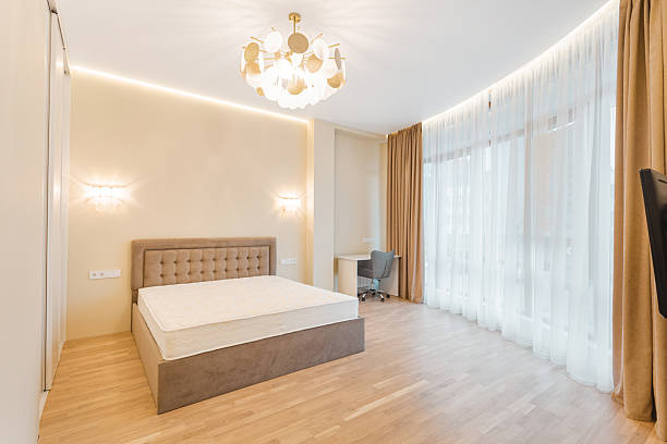 istock Modern bedroom with wooden floor, large windows, and elegant lighting during daylight hours 2229285700