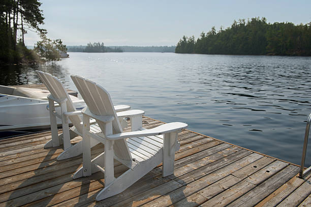 istock Two white chairs frame a boat on a still morning lake 2229290190