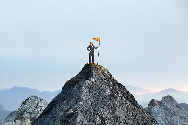 istock Woman Planting A Flag On A Mountain Peak 2229291995