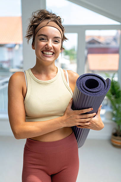 istock Young woman posing with a yoga mat inside a bright studio 2229296413