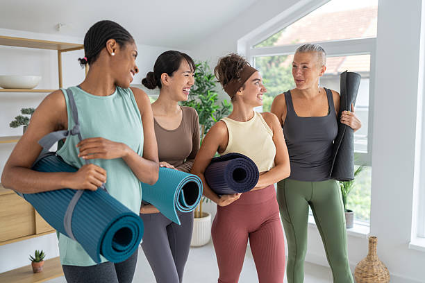 istock Four women in a yoga studio holding mats and sharing joyful conversation 2229301392