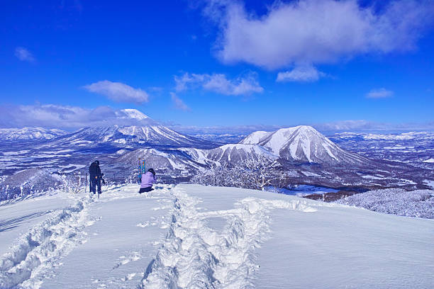 Rusutu, Hokkaido - February 6, 2024: Skiers view Mount Yotei from off-piste in the East Area at Rusutsu Ski Resort in Hokkaido, Japan, on a clear winter day.