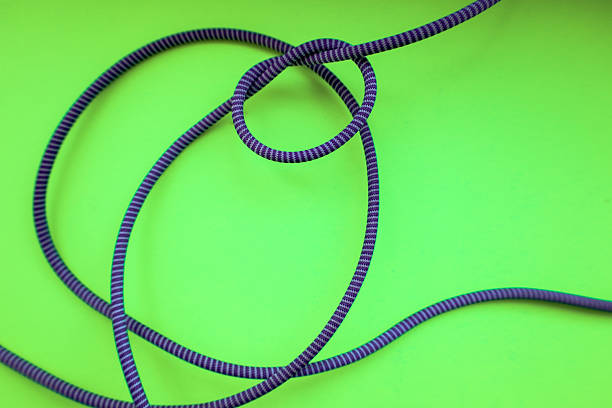 istock A vibrant purple rope, twisted into a knot, rests on a bright green background, creating a dynamic and contrasting visual effect. The shot emphasizes the texture and form of the rope. 2229322272