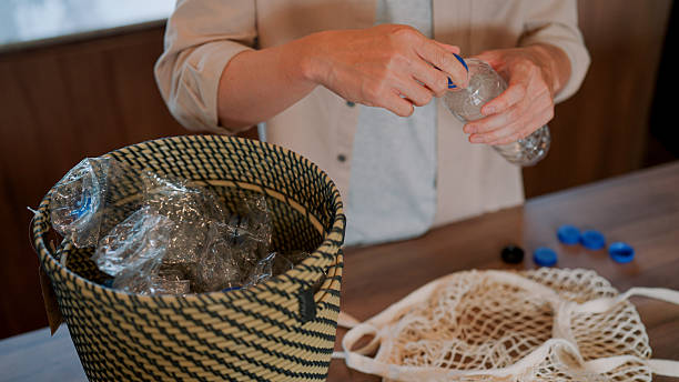 istock Man crushing plastic bottles before putting them in recycle basket. 2229326216