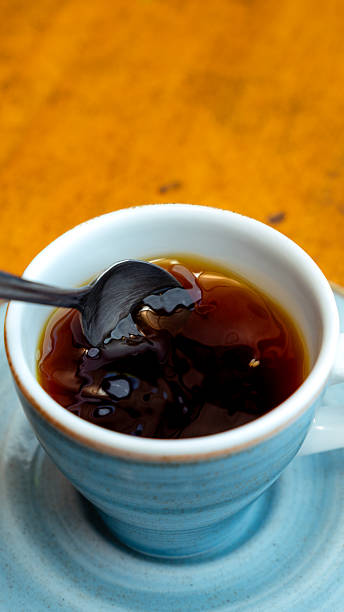 istock Spoon stirring black coffee in blue ceramic cup on wooden table 2229327657