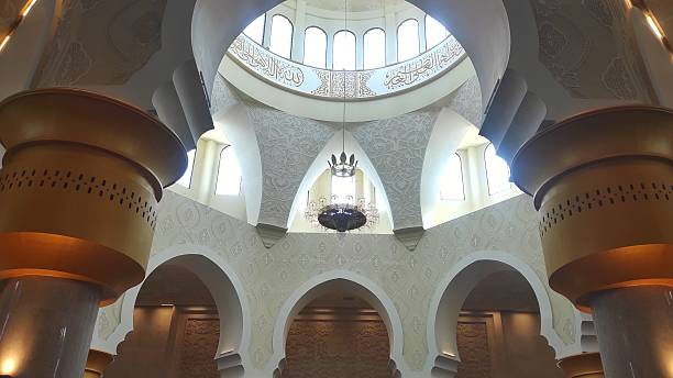 istock An elegant mosque interior featuring a grand dome adorned with Arabic calligraphy, intricate wall patterns, golden columns, and a magnificent chandelier radiating timeless beauty. 2229337433