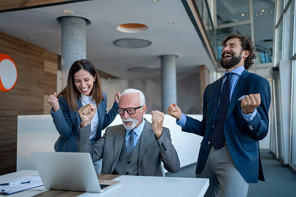 istock Business team celebrating success while looking at laptop 2229339512